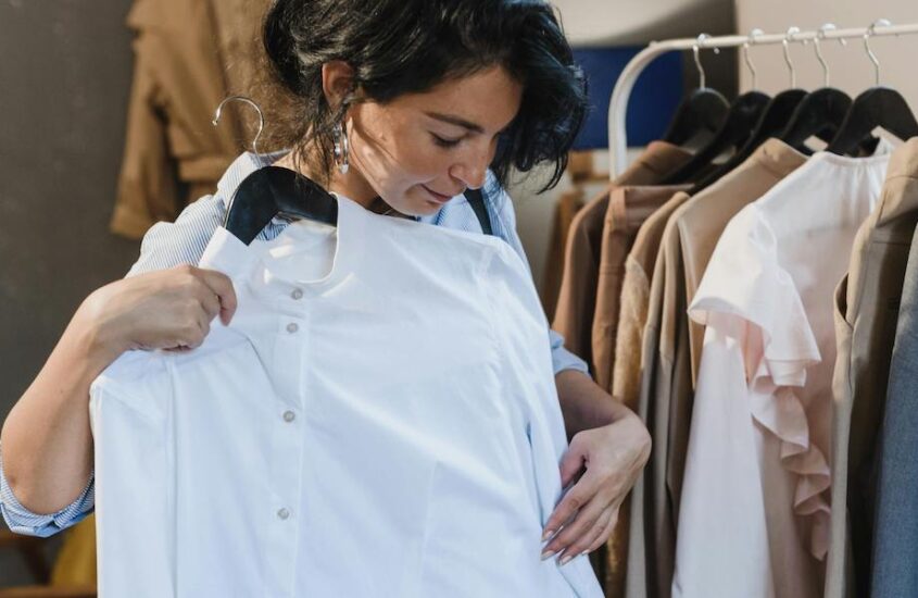 Woman putting a white shirt against her to check if it fits.