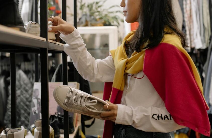 Woman shopping for clothes at a store and holding shoes.